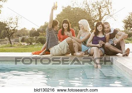Friends relaxing together by swimming pool View Large Photo Image Stock Photograph - Friends relaxing together by swimming pool. Fotosearch