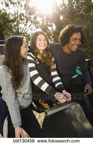 Stock Photo - Friends sitting together in truck bed. Fotosearch