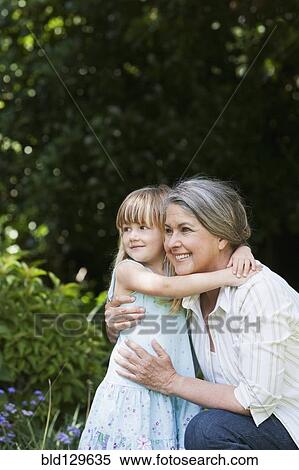 Stock Photography - Grandmother and granddaughter hugging in garden. Fotosearch