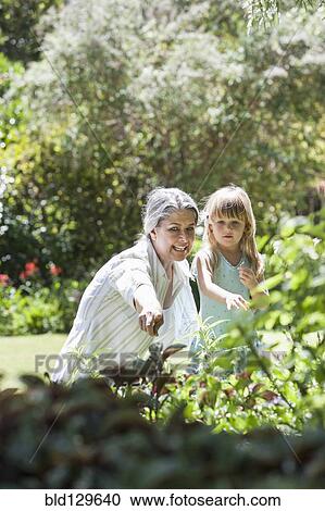 Grandmother and granddaughter in garden View Large Photo Image Stock Image - Grandmother and granddaughter in garden. Fotosearch