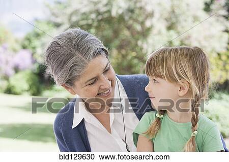 Stock Image - Grandmother and granddaughter smiling outdoors. Fotosearch