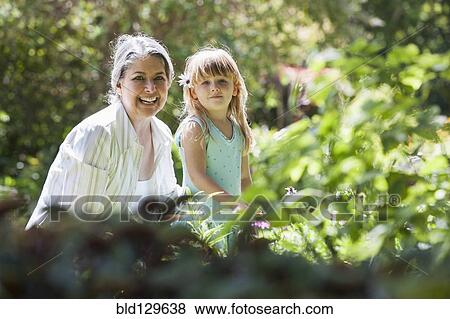 Stock Photo - Grandmother and granddaughter smiling in garden. Fotosearch
