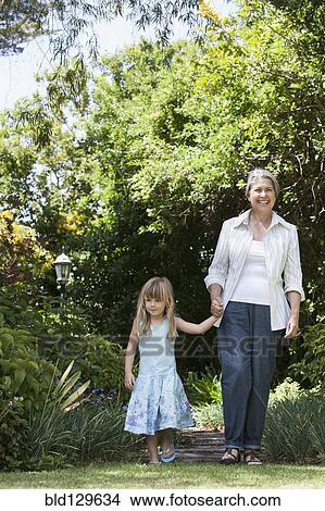 Grandmother and granddaughter walking in garden View Large Photo Image Picture - Grandmother and granddaughter walking in garden. Fotosearch