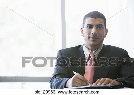Hispanic businessman making notes in office View Large Photo Image Stock Image - Hispanic businessman making notes in office. Fotosearch