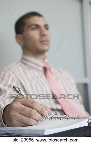 Hispanic businessman taking notes in office View Large Photo Image Stock Photograph - Hispanic businessman taking notes in office. Fotosearch