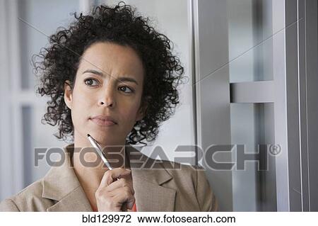 Stock Image - Hispanic businesswoman thinking in office. Fotosearch