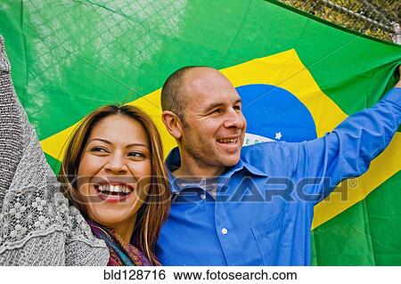Hispanic couple holding Brazilian flag View Large Photo Image Stock Photograph - Hispanic couple holding Brazilian flag. Fotosearch
