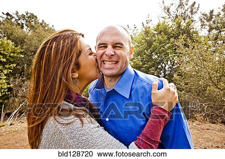 Stock Image - Hispanic couple kissing in park. Fotosearch