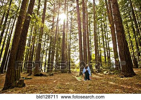 Stock Image - Hispanic couple wrapped in blanket in forest. Fotosearch
