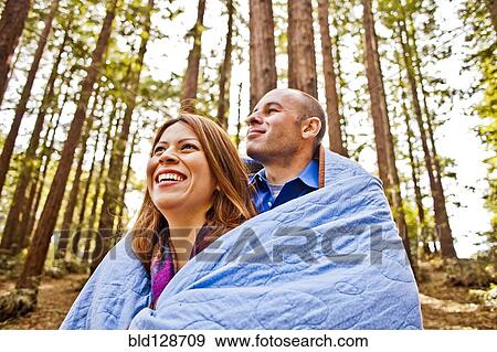 Hispanic couple wrapped in blanket in forest View Large Photo Image Stock Photo - Hispanic couple wrapped in blanket in forest. Fotosearch