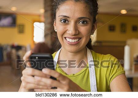 Hispanic server using cell phone in cafe View Large Photo Image Stock Photograph - Hispanic server using cell phone in cafe. Fotosearch