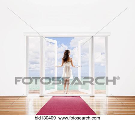 Hispanic woman opening French doors to ocean view View Large Photo Image Stock Photo - Hispanic woman opening French doors to ocean view. Fotosearch