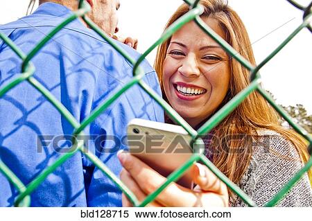Stock Photography - Hispanic woman with boyfriend using cell phone. Fotosearch