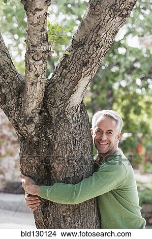 Man hugging tree outdoors View Large Photo Image Picture - Man hugging tree outdoors. Fotosearch