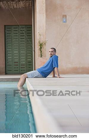 Man relaxing by swimming pool View Large Photo Image Stock Image - Man relaxing by swimming pool. Fotosearch