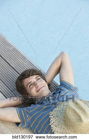 Stock Photo - Man relaxing by swimming pool. Fotosearch