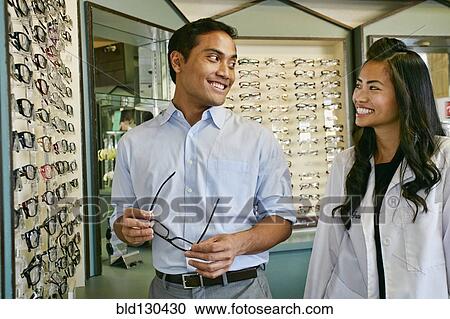 Stock Image - Man trying on glasses at optometrist. Fotosearch