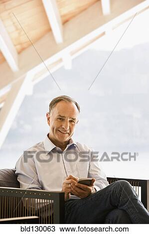Man using cell phone in armchair View Large Photo Image Stock Image - Man using cell phone in armchair. Fotosearch