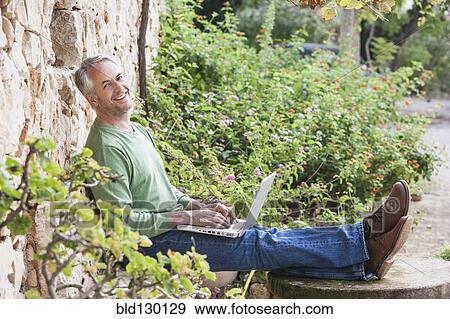 Man using laptop in backyard View Large Photo Image Stock Photo - Man using laptop in backyard. Fotosearch