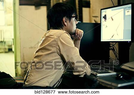 Stock Photo - Mari man using computer at desk. Fotosearch