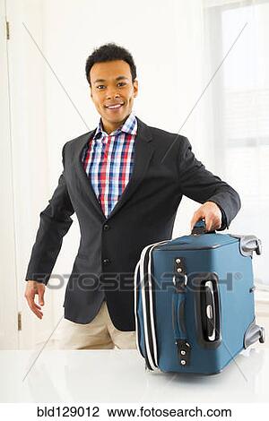 Stock Image - Mixed race businessman carrying suitcase. Fotosearch