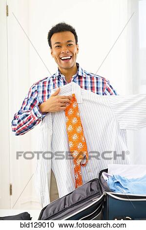 Mixed race businessman packing suitcase View Large Photo Image Stock Image - Mixed race businessman packing suitcase. Fotosearch