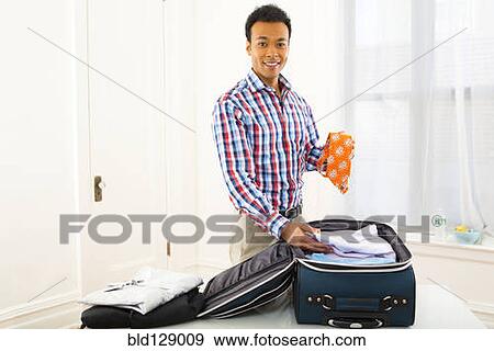 Stock Photo - Mixed race businessman packing suitcase. Fotosearch