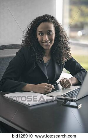 Mixed race businesswoman smiling at desk View Large Photo Image Stock Image - Mixed race businesswoman smiling at desk. Fotosearch