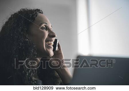 Stock Photo - Mixed race businesswoman talking on cell phone. Fotosearch