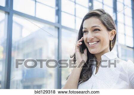 Stock Photo - Mixed race businesswoman talking on cell phone outdoors. Fotosearch