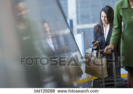 Stock Photo - Mixed race businesswoman using cell phone on escalator. Fotosearch