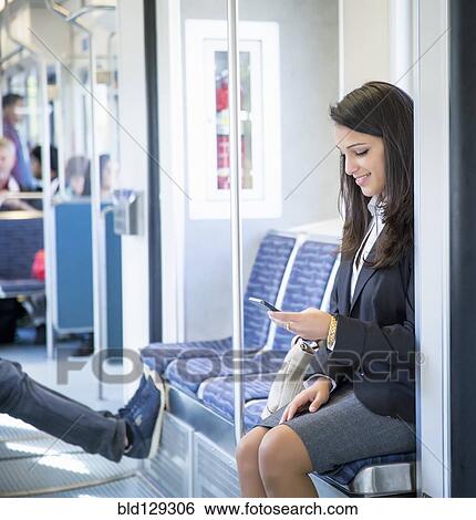 Stock Photograph - Mixed race businesswoman using cell phone on train. Fotosearch