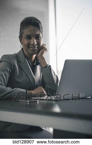 Mixed race businesswoman using laptop at desk View Large Photo Image Stock Photo - Mixed race businesswoman using laptop at desk. Fotosearch