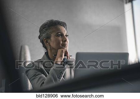 Stock Photograph - Mixed race businesswoman using laptop in office. Fotosearch