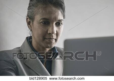 Mixed race businesswoman using laptop View Large Photo Image Stock Photography - Mixed race businesswoman using laptop. Fotosearch