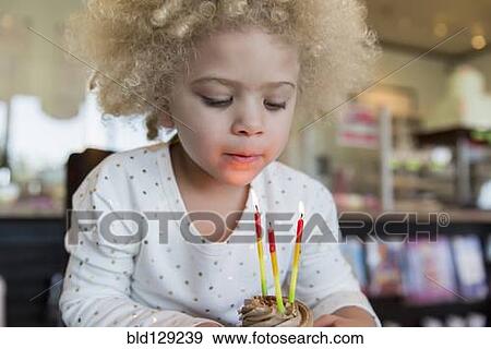 Mixed race girl blowing candles on cupcake View Large Photo Image Stock Photo - Mixed race girl blowing candles on cupcake. Fotosearch