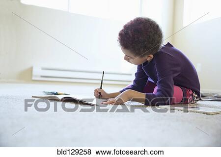 Stock Photo - Mixed race girl drawing on bedroom floor. Fotosearch