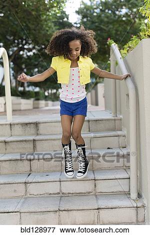 Stock Photo - Mixed race girl jumping on steps. Fotosearch