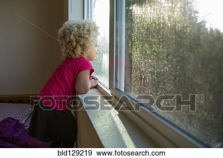 Stock Photo - Mixed race girl looking out window. Fotosearch