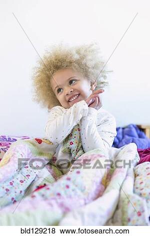 Stock Photo - Mixed race girl smiling in bed. Fotosearch