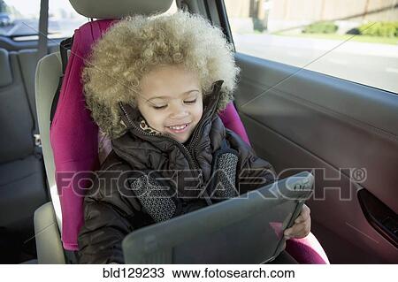 Mixed race girl using digital tablet in back seat of car View Large Photo Image Stock Image - Mixed race girl using digital tablet in back seat of car. Fotosearch