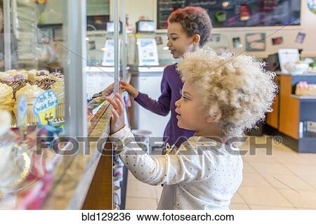Mixed race girls picking cupcakes in bakery View Large Photo Image Stock Photograph - Mixed race girls picking cupcakes in bakery. Fotosearch
