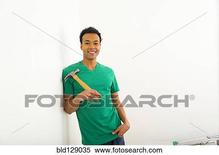 Stock Photography - Mixed race man holding hammer. Fotosearch
