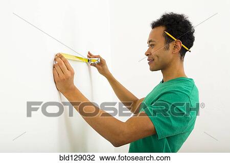 Mixed race man measuring wall View Large Photo Image Stock Image - Mixed race man measuring wall. Fotosearch
