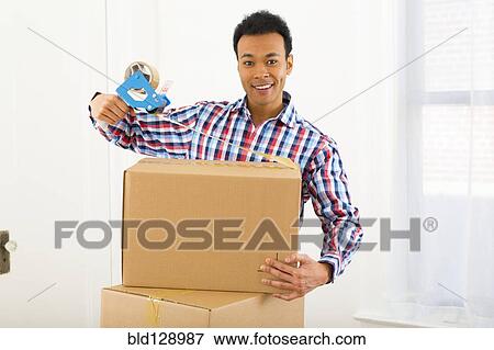 Mixed race man packing cardboard boxes View Large Photo Image Stock Photo - Mixed race man packing cardboard boxes. Fotosearch