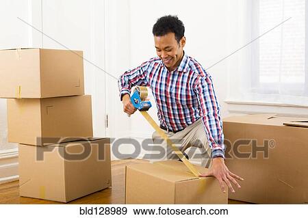 Mixed race man packing cardboard boxes View Large Photo Image Stock Photo - Mixed race man packing cardboard boxes. Fotosearch