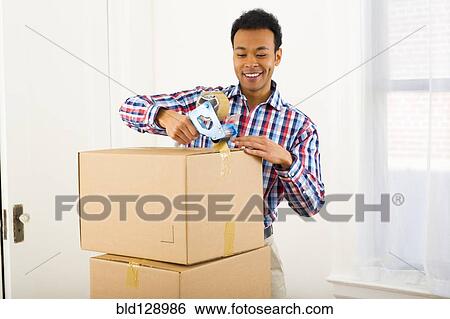 Mixed race man packing cardboard boxes View Large Photo Image Stock Photograph - Mixed race man packing cardboard boxes. Fotosearch