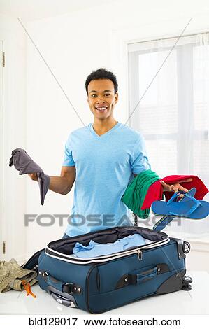 Mixed race man packing suitcase View Large Photo Image Stock Photo - Mixed race man packing suitcase. Fotosearch