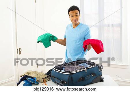 Mixed race man packing suitcase View Large Photo Image Stock Photograph - Mixed race man packing suitcase. Fotosearch