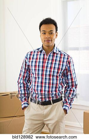Stock Image - Mixed race man standing in new home. Fotosearch